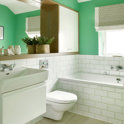 Example of a mid-sized transitional master white tile and subway tile porcelain tile alcove bathtub design in London with a console sink, flat-panel cabinets, white cabinets, a wall-mount toilet and green walls