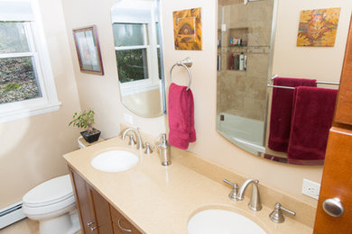 Medium sized traditional ensuite bathroom in New York with shaker cabinets, medium wood cabinets, an alcove bath, a shower/bath combination, a one-piece toilet, beige tiles, porcelain tiles, beige walls, porcelain flooring, a submerged sink, engineered stone worktops, beige floors and a sliding door.