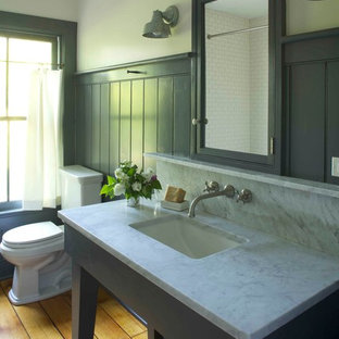 Inspiration for a cottage medium tone wood floor bathroom remodel in New York with marble countertops, an undermount sink, a two-piece toilet and gray walls