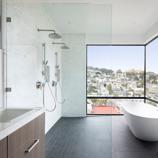 Foto de cuarto de baño contemporáneo con armarios con paneles lisos, puertas de armario de madera en tonos medios, bañera exenta, lavabo bajoencimera, suelo negro y encimeras blancas