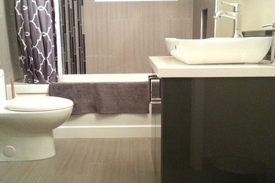 Пример оригинального дизайна: главная ванная комната среднего размера в современном стиле с плоскими фасадами, черными фасадами, ванной в нише, душем над ванной, унитазом-моноблоком, бежевыми стенами, полом из винила, настольной раковиной и столешницей из искусственного камня