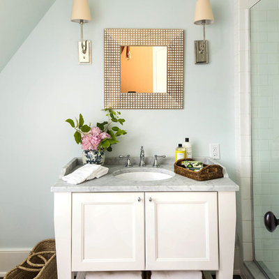 Mid-sized elegant 3/4 white tile and subway tile dark wood floor and brown floor alcove shower photo in Birmingham with white cabinets, recessed-panel cabinets, blue walls, an undermount sink, marble countertops, a hinged shower door and gray countertops
