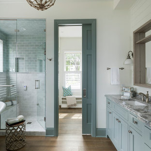 Esempio di una stanza da bagno padronale costiera con ante con riquadro incassato, ante turchesi, vasca con piedi a zampa di leone, doccia alcova, pareti bianche, pavimento in legno massello medio, lavabo sottopiano, pavimento marrone e porta doccia a battente