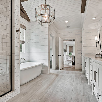 Freestanding bathtub - cottage gray floor freestanding bathtub idea in Other with recessed-panel cabinets, white cabinets, white walls, an undermount sink and white countertops