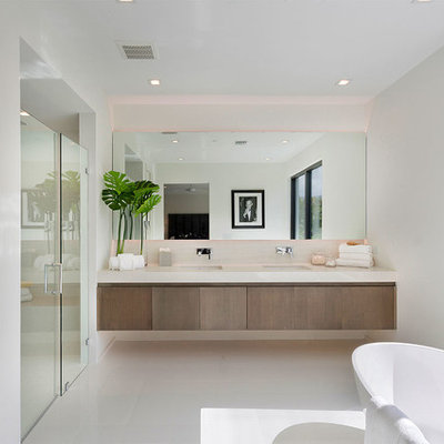 Example of a trendy master white floor bathroom design in Miami with flat-panel cabinets, medium tone wood cabinets, white walls, an undermount sink, a hinged shower door and white countertops