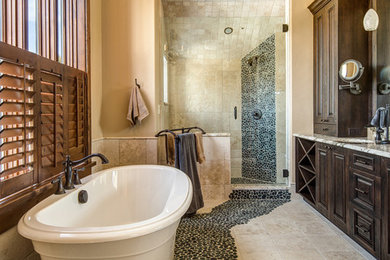 Inspiration for a large rustic ensuite bathroom in Denver with a built-in sink, raised-panel cabinets, dark wood cabinets, marble worktops, a japanese bath, a walk-in shower, a two-piece toilet, multi-coloured tiles, stone tiles, beige walls and travertine flooring.