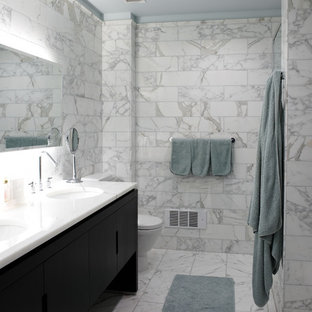 Trendy white tile and marble tile marble floor bathroom photo in New York with an undermount sink, flat-panel cabinets, black cabinets and marble countertops