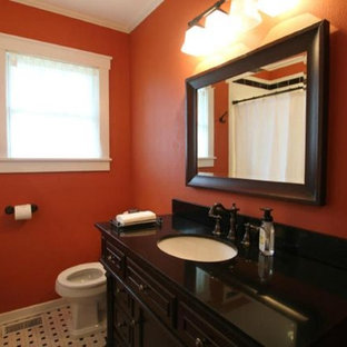 Kleines Rustikales Kinderbad mit verzierten Schränken, dunklen Holzschränken, Badewanne in Nische, Duschbadewanne, Wandtoilette mit Spülkasten, schwarz-weißen Fliesen, Keramikfliesen, oranger Wandfarbe, Keramikboden, integriertem Waschbecken und Granit-Waschbecken/Waschtisch in Sonstige