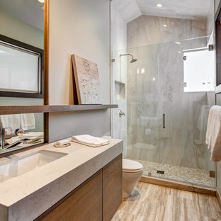 Esempio di una stanza da bagno padronale moderna di medie dimensioni con ante lisce, ante in legno bruno, doccia alcova, WC monopezzo, piastrelle beige, piastrelle grigie, lastra di pietra, pareti grigie, pavimento in gres porcellanato, lavabo sottopiano, top in laminato, pavimento marrone e porta doccia a battente