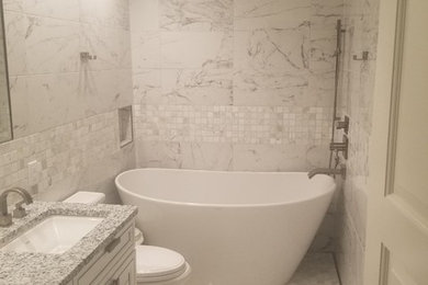 Freestanding bathtub - mid-sized transitional master gray tile, white tile and marble tile marble floor and gray floor freestanding bathtub idea in Other with raised-panel cabinets, white cabinets, gray walls, an undermount sink, granite countertops and gray countertops
