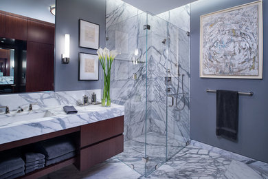 Corner shower - mid-sized contemporary master gray tile and marble tile marble floor and multicolored floor corner shower idea in New York with an undermount sink, flat-panel cabinets, medium tone wood cabinets, marble countertops, gray walls and a hinged shower door