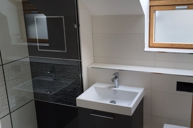 Medium sized contemporary ensuite bathroom in Dorset with flat-panel cabinets, grey cabinets, a walk-in shower, a wall mounted toilet, black and white tiles, ceramic tiles, white walls, porcelain flooring and a wall-mounted sink.