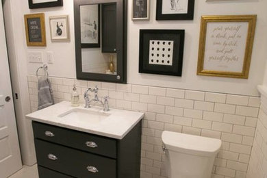 Klassisk inredning av ett en-suite badrum, med marmorbänkskiva, ett undermonterad handfat, släta luckor, skåp i mörkt trä, ett platsbyggt badkar, en dusch/badkar-kombination, en toalettstol med separat cisternkåpa, vit kakel, tunnelbanekakel, vita väggar och klinkergolv i keramik
