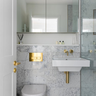 This is an example of a small classic shower room bathroom in London with an alcove bath, an alcove shower, a wall mounted toilet, grey tiles, a wall-mounted sink, grey floors, a hinged door and a single sink.