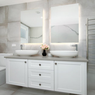 This is an example of a large beach style master bathroom in Sydney with shaker cabinets, white cabinets, gray tile, ceramic tile, ceramic floors, engineered quartz benchtops, grey floor, grey benchtops, a vessel sink and a double vanity.
