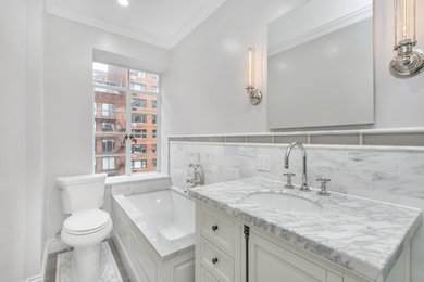 Small transitional master white tile and mosaic tile marble floor and gray floor bathroom photo in New York with recessed-panel cabinets, a two-piece toilet, gray walls, a drop-in sink, marble countertops and white cabinets