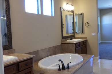 Example of a large mountain style master brown tile and stone tile marble floor bathroom design in Phoenix with a drop-in sink, raised-panel cabinets, medium tone wood cabinets, marble countertops, a two-piece toilet and beige walls