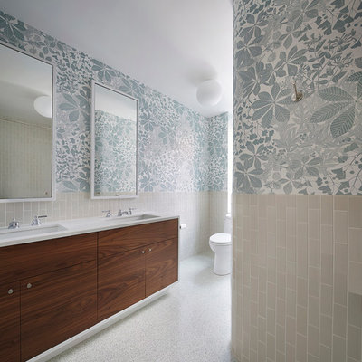 Example of a trendy beige tile and ceramic tile bathroom design in New York with flat-panel cabinets, dark wood cabinets, multicolored walls, an undermount sink, a one-piece toilet and solid surface countertops