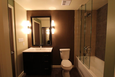 トロントにある中くらいなコンテンポラリースタイルのおしゃれなマスターバスルーム (フラットパネル扉のキャビネット、黒いキャビネット、ドロップイン型浴槽、シャワー付き浴槽	、一体型トイレ	、茶色い壁、一体型シンク、ラミネートカウンター) の写真