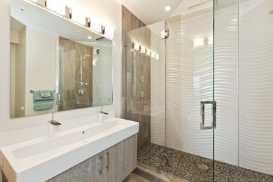 Imagen de cuarto de baño actual con lavabo de seno grande, armarios con paneles lisos, ducha empotrada y suelo de baldosas tipo guijarro