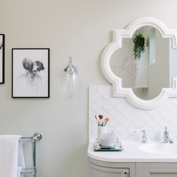 A fresh green with marble bathroom with cleverly concealed laundry