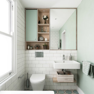 Design ideas for a scandinavian bathroom in London with flat-panel cabinets, green cabinets, a wall-mount toilet, white tile, subway tile, green walls, a wall-mount sink and multi-coloured floor.
