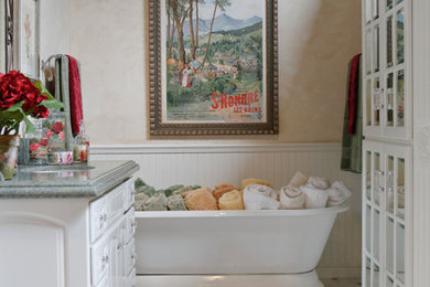 ロサンゼルスにある中くらいなトラディショナルスタイルのおしゃれな浴室 (アンダーカウンター洗面器、レイズドパネル扉のキャビネット、白いキャビネット、大理石の洗面台、置き型浴槽、白いタイル、石タイル、ベージュの壁、大理石の床) の写真
