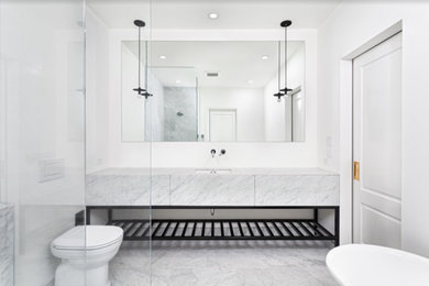 Inspiration for a mid-sized modern master marble tile marble floor and white floor bathroom remodel in Ottawa with flat-panel cabinets, white cabinets, a one-piece toilet, white walls, an undermount sink, marble countertops and white countertops