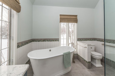 デトロイトにある高級な広いトランジショナルスタイルのおしゃれなマスターバスルーム (フラットパネル扉のキャビネット、青いキャビネット、置き型浴槽、バリアフリー、分離型トイレ、白いタイル、セラミックタイル、緑の壁、セラミックタイルの床、アンダーカウンター洗面器、クオーツストーンの洗面台、グレーの床、開き戸のシャワー、白い洗面カウンター) の写真