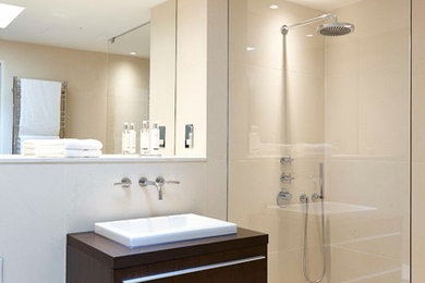 На фото: ванная комната в современном стиле с накладной раковиной, плоскими фасадами, темными деревянными фасадами, душем без бортиков, инсталляцией и бежевой плиткой