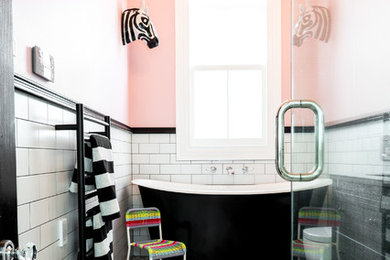 Inspiration for a medium sized eclectic family bathroom in Auckland with freestanding cabinets, distressed cabinets, a freestanding bath, a corner shower, a one-piece toilet, black and white tiles, porcelain tiles, pink walls, porcelain flooring, a submerged sink and granite worktops.