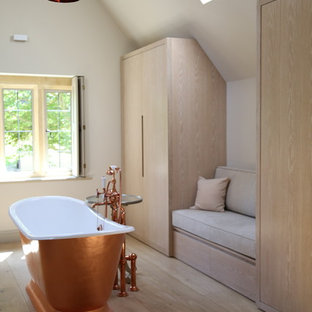 Inspiration for a medium sized contemporary ensuite bathroom in Gloucestershire with flat-panel cabinets, beige cabinets, a freestanding bath, white walls, light hardwood flooring and beige floors.