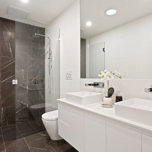 Contemporary bathroom in Melbourne with flat-panel cabinets, white cabinets, a curbless shower, gray tile, white walls, a vessel sink, grey floor, a hinged shower door and white benchtops.