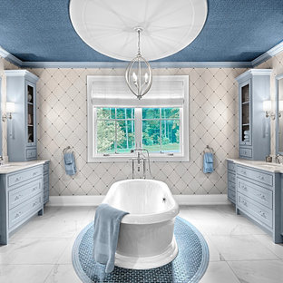 Freestanding bathtub - large cottage master marble floor, white floor, double-sink, wallpaper ceiling and wallpaper freestanding bathtub idea in Grand Rapids with raised-panel cabinets, blue cabinets, multicolored walls, an undermount sink, quartzite countertops, white countertops and a built-in vanity