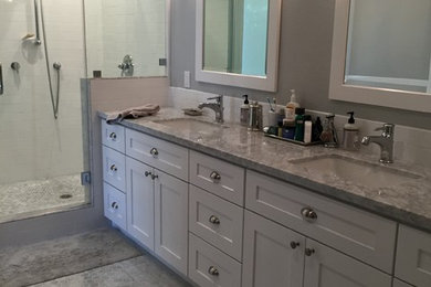 サンフランシスコにある広いトランジショナルスタイルのおしゃれなマスターバスルーム (アンダーカウンター洗面器、シェーカースタイル扉のキャビネット、白いキャビネット、大理石の洗面台、アンダーマウント型浴槽、コーナー設置型シャワー、一体型トイレ	、白いタイル、セラミックタイル、グレーの壁、大理石の床) の写真