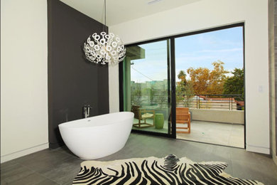 Foto de cuarto de baño principal actual grande con bañera exenta, paredes blancas y suelo gris