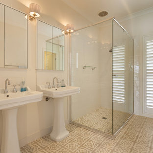 Design ideas for a mid-sized beach style master bathroom in Other with a corner shower, white tile, white walls, a pedestal sink, beige floor, a sliding shower screen and cement tiles.
