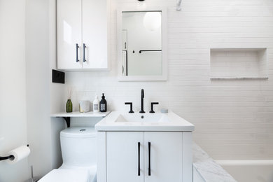 Example of a mid-sized transitional 3/4 white tile and subway tile ceramic tile and beige floor bathroom design in New York with flat-panel cabinets, white cabinets, a two-piece toilet, white walls, an integrated sink, marble countertops and gray countertops