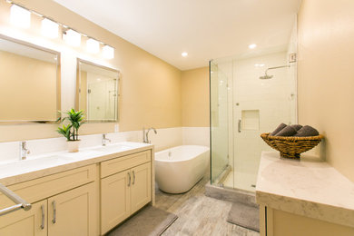 Example of a large transitional master white tile and ceramic tile laminate floor and brown floor bathroom design in Hawaii with shaker cabinets, white cabinets, beige walls, an undermount sink, quartzite countertops, a hinged shower door and white countertops