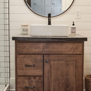 Alcove shower - small country 3/4 white tile and ceramic tile ceramic tile, gray floor, single-sink and shiplap wall alcove shower idea in Other with shaker cabinets, brown cabinets, a one-piece toilet, white walls, a vessel sink, concrete countertops, a hinged shower door, gray countertops and a freestanding vanity