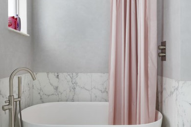 Immagine di una stanza da bagno minimal di medie dimensioni con vasca freestanding, piastrelle di marmo, pareti grigie, pavimento in marmo e pavimento bianco