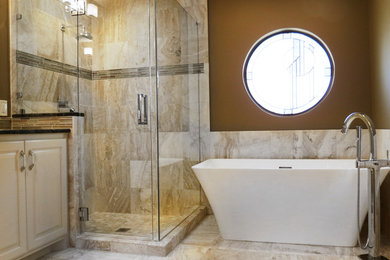 Photo of a medium sized modern ensuite bathroom in Dallas with a submerged sink, raised-panel cabinets, white cabinets, granite worktops, a freestanding bath, a walk-in shower, a two-piece toilet, beige tiles, stone tiles, brown walls and travertine flooring.