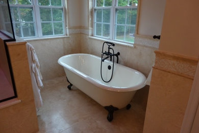 Modelo de cuarto de baño principal clásico grande con lavabo bajoencimera, bañera con patas, combinación de ducha y bañera, sanitario de dos piezas, baldosas y/o azulejos beige y suelo con mosaicos de baldosas