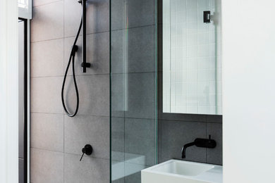 Ispirazione per una stanza da bagno design di medie dimensioni con doccia aperta, piastrelle grigie, piastrelle in ceramica, pareti grigie, pavimento con piastrelle in ceramica, lavabo sospeso, pavimento bianco e doccia aperta