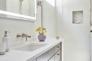 ロサンゼルスにある高級なコンテンポラリースタイルのおしゃれな浴室 (フラットパネル扉のキャビネット、アルコーブ型シャワー、ガラスタイル、磁器タイルの床、アンダーカウンター洗面器、クオーツストーンの洗面台、開き戸のシャワー、白い洗面カウンター) の写真