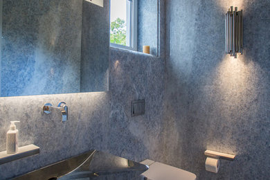 Diseño de cuarto de baño principal contemporáneo de tamaño medio con sanitario de pared, baldosas y/o azulejos grises, baldosas y/o azulejos de mármol, paredes grises, suelo de mármol, lavabo suspendido, encimera de acero inoxidable y suelo gris