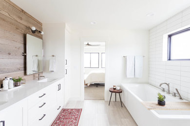Diseño de cuarto de baño campestre con armarios estilo shaker, puertas de armario blancas, bañera esquinera, baldosas y/o azulejos blancos, paredes blancas, lavabo bajoencimera, suelo gris y encimeras blancas