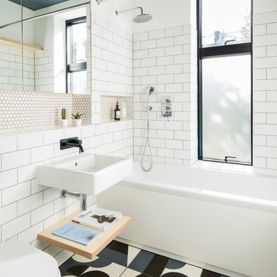 Example of a mid-sized danish white tile and subway tile ceramic tile and multicolored floor bathroom design in London with white walls, a wall-mount sink and a wall-mount toilet