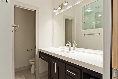 ヒューストンにあるお手頃価格の中くらいなトラディショナルスタイルのおしゃれな浴室 (シェーカースタイル扉のキャビネット、黒いキャビネット、アルコーブ型シャワー、白い壁、淡色無垢フローリング、アンダーカウンター洗面器、人工大理石カウンター) の写真