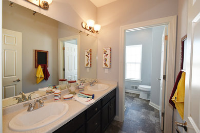 Mid-sized elegant kids' brown tile linoleum floor tub/shower combo photo in Milwaukee with a drop-in sink, raised-panel cabinets, dark wood cabinets, laminate countertops and gray walls